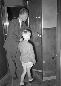 803545 Afbeelding van een vader die zijn zoontje naar de W.C. brengt in een rijtuig van de N.S.